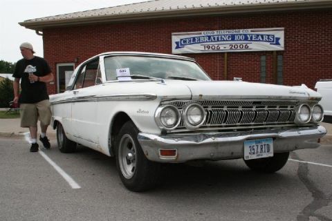 1979 Ford Bronco - A white 1962 Mercury Meteor is parked in front of a brick building with a banner celebrating 100 years.