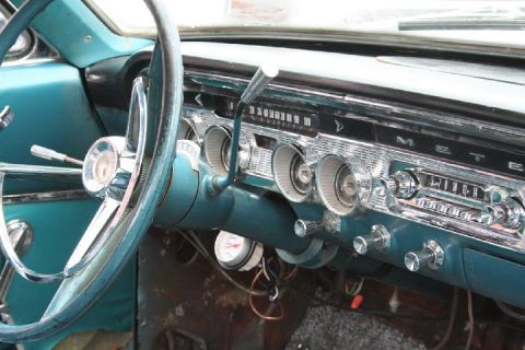 1979 Ford Bronco - The interior of a vintage car features a teal dashboard, a large steering wheel, and a classic radio.
