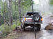 1989 Ford Bronco - An SUV navigates a muddy, wooded path with a spare tire visible on the rear.