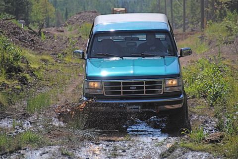 1996 Ford Bronco - Ford Bronco navigates a challenging muddy off-road path.
