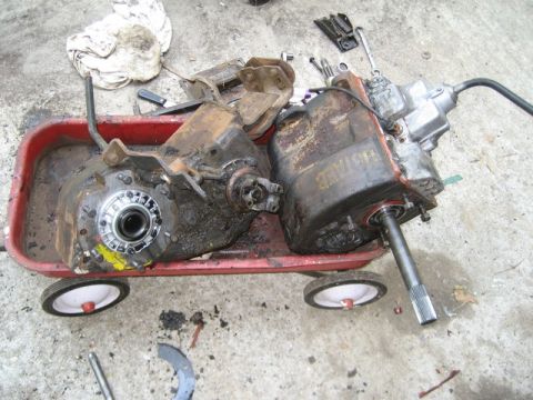 1995 Ford Bronco - Two transfer cases are shown resting in a red wagon, with tools scattered around them on the ground.