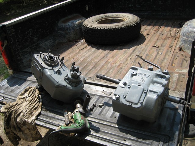 Two gray transfer cases and a spare tire in the bed of a pickup truck.