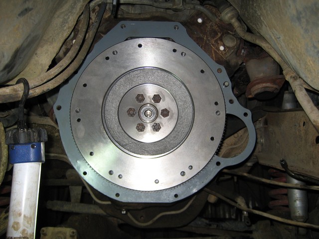Close-up of a vehicle's flywheel and adapter plate installed on the transmission bellhousing.