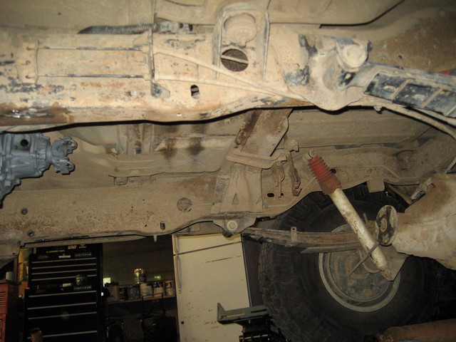 Underside of a 1995 Ford Bronco, showing transmission, leaf springs, and shock absorber.