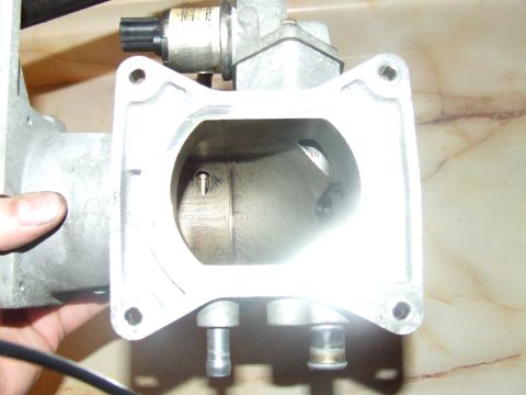 2003 Ford Crown Victoria - A close-up view of a throttle body assembly, likely from a Ford Crown Victoria, showing the internal bore and attached electronic component…