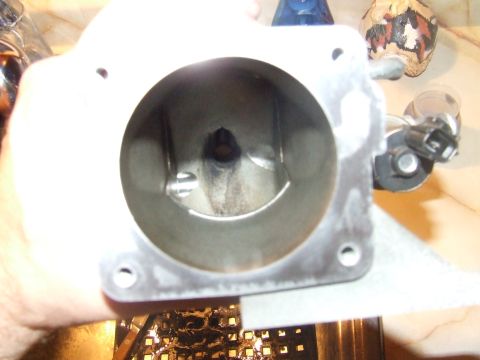 2003 Ford Crown Victoria - A close-up view of the inside of a throttle body, likely from a 2003 Ford Crown Victoria, showing some carbon buildup. The throttle body is…