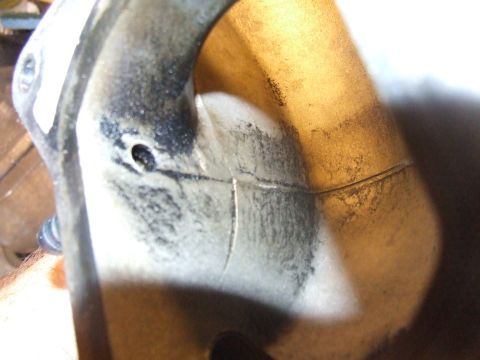 2003 Ford Crown Victoria - A close-up view shows a cracked metal part, possibly an exhaust manifold or intake component, with significant carbon buildup and discolora…