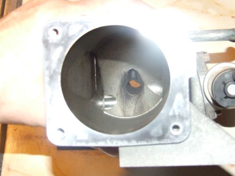 2003 Ford Crown Victoria - A close-up, angled view inside a metal housing, likely a throttle body, showing a circular opening with a flap mechanism. The housing appea…