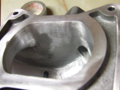 2003 Ford Crown Victoria - A close-up view of the polished interior of a metal engine intake manifold, possibly for a 2003 Ford Crown Victoria. A roll of tape with "A…