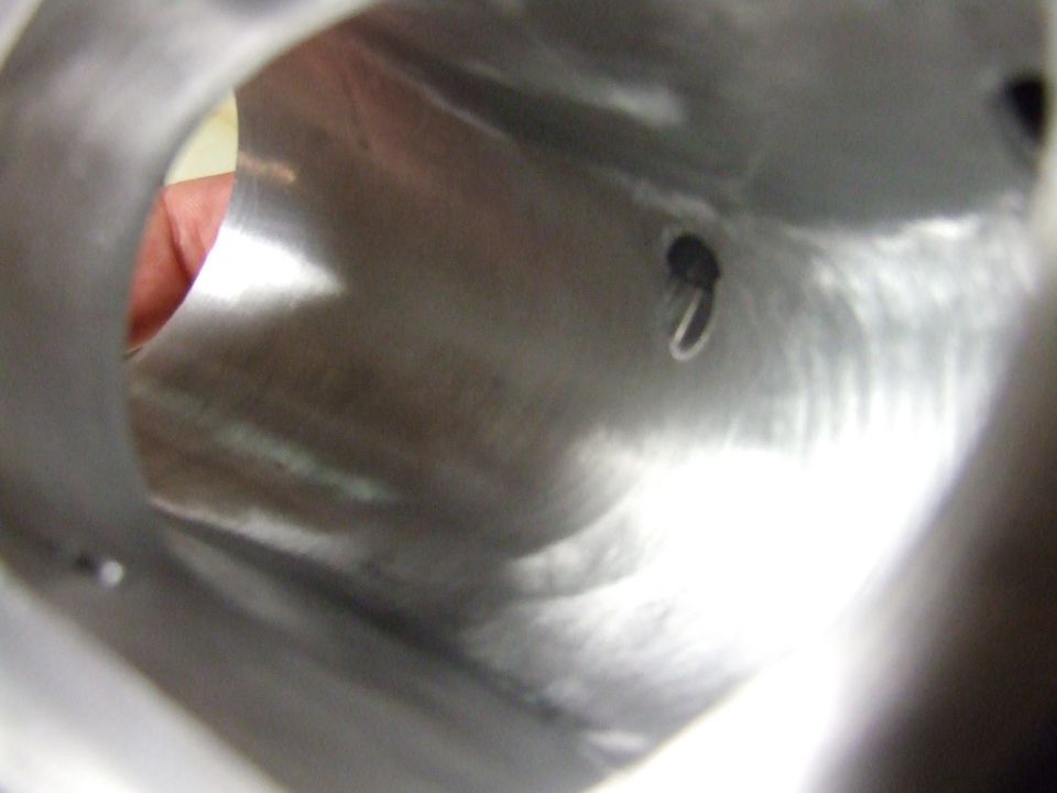 Interior view of a metallic tube with a small black object and a silver ring.