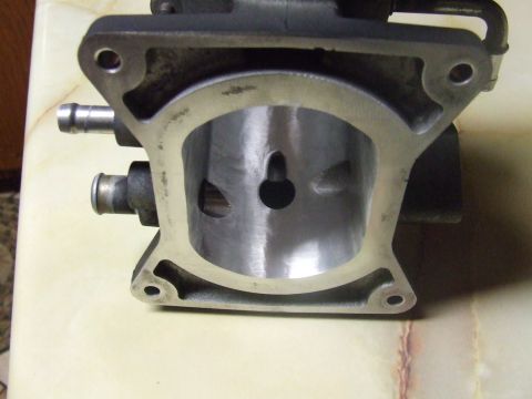 2003 Ford Crown Victoria - A close-up, top-down view of a machined metal automotive part, likely a throttle body or intake manifold, with two small hose fittings visi…
