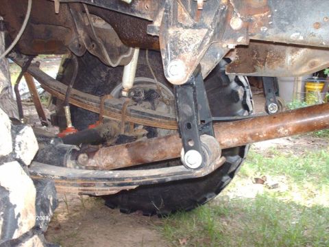 1990 Ford F-150 - The underside of a vintage pickup truck shows the suspension system, including leaf springs, shocks, and a differential. The vehicle appear…
