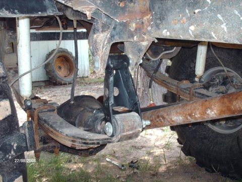 1990 Ford F-150 - The underside of a vehicle shows a leaf spring suspension system with a shock absorber and a U-bolt securing the axle to the leaf springs.…