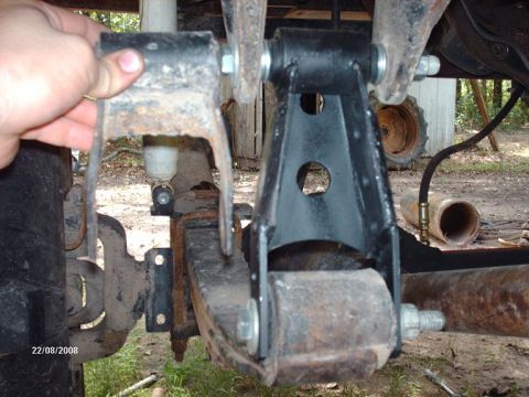 1990 Ford F-150 - A close-up view of the rear suspension components of a vehicle, likely a 1990 Ford F-150, showing a leaf spring, a shock absorber, and a bl…