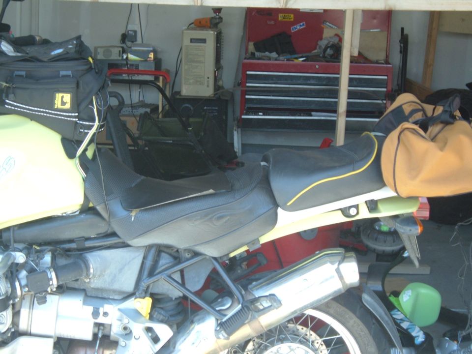 Yellow and black motorcycle in a garage with storage and tools.