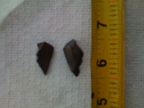 1966 Ford Bronco - Two small, dark, irregularly shaped fragments are shown next to a yellow measuring tape. The fragments appear to be broken pieces of a larg…