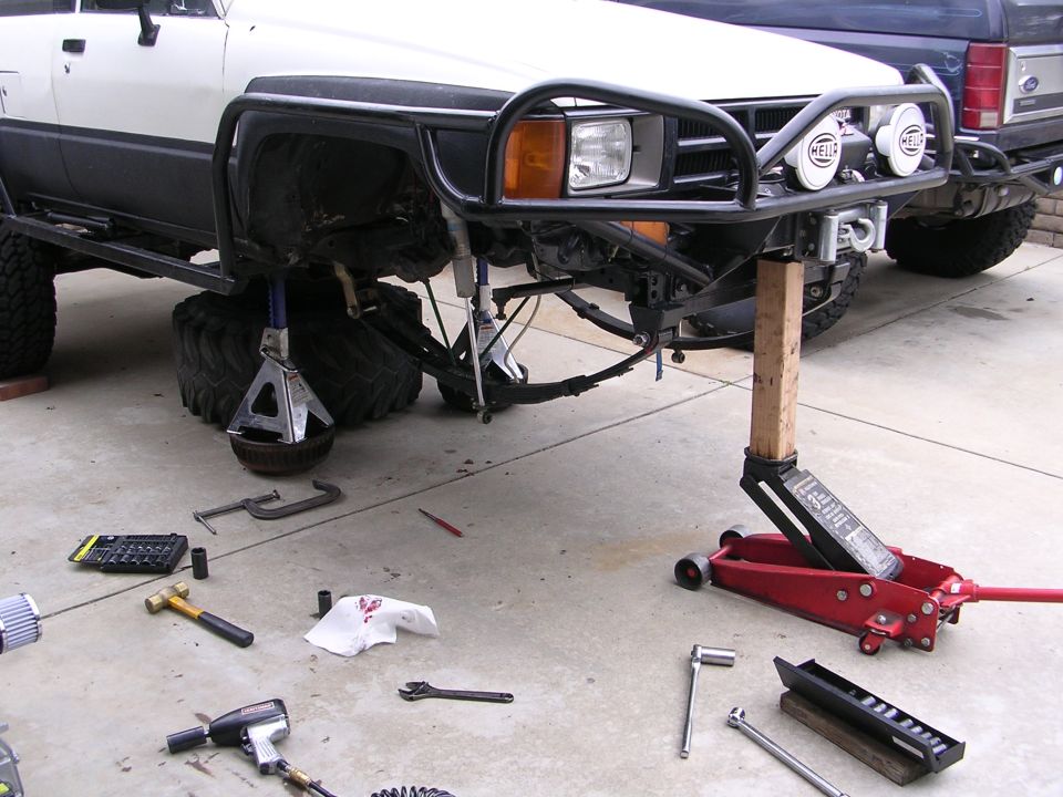 White Toyota 4Runner on jack stands with tools on the ground.