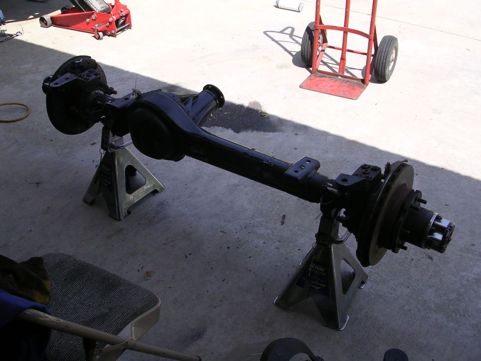 Black rear axle assembly with disc brakes on jack stands.