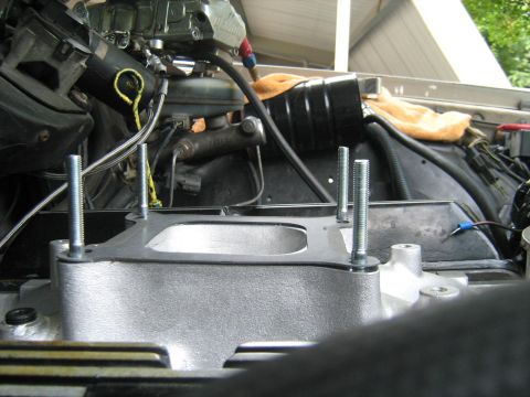 1988 Mercury Grand Marquis - Two threaded studs protrude from a silver intake manifold gasket, ready for installation onto an engine. The surrounding engine bay shows v…