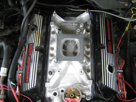 1988 Mercury Grand Marquis - A close-up view of a Ford V8 engine with "Ford Motorsport" branded valve covers and a silver Weiand intake manifold. Red spark plug wires a…