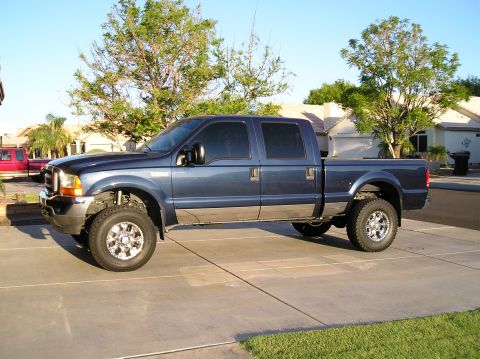1986 Toyota Hilux - A dark blue Ford F-Series Super Duty pickup truck is parked on a concrete driveway in front of a suburban house. The truck has tinted windo…