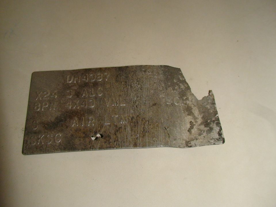 Weathered embossed Ford metal ID tag with a torn edge, partly legible codes including 4X4