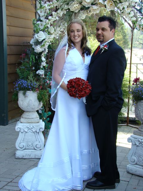 1989 Ford Bronco - A bride and groom pose for a wedding photo outdoors under a floral archway.