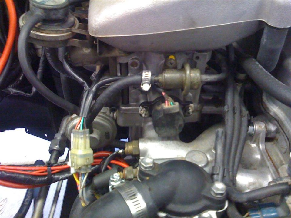 Engine bay closeup showing wiring connectors, vacuum lines and hose clamps