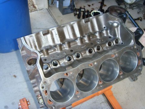 1989 Ford F-250 - A bare V8 engine block, likely from a Ford truck, is shown resting on an orange engine stand. The block is made of cast iron and has four v…