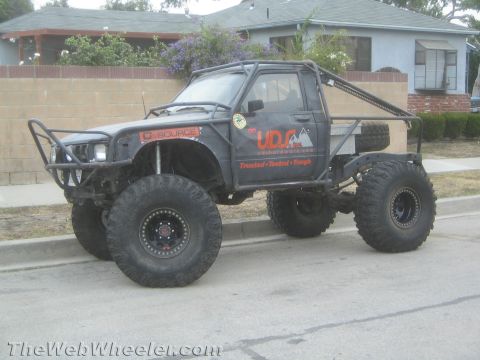 1990 Ford Bronco - Photo of a black lifted Toyota mini-truck rock buggy on a street, not a technical document.