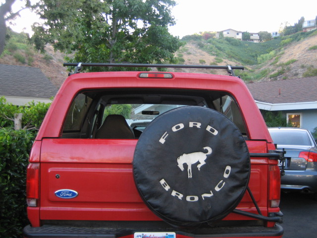Red SUV's rear view, spare tire mounted on the tailgate, visible taillights and bumper