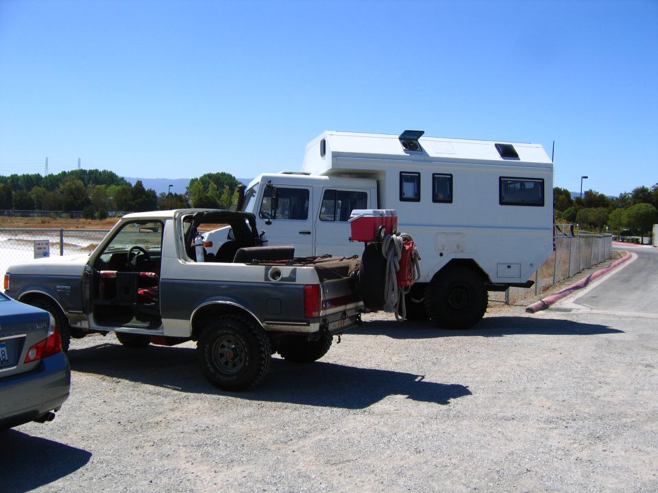 1991 Ford Bronco convertible with camper truck behind it