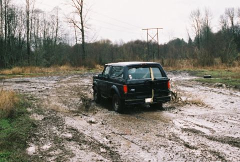 1995 Ford Bronco - This black 1995 Ford Bronco navigates a muddy track, kicking up water as it goes.