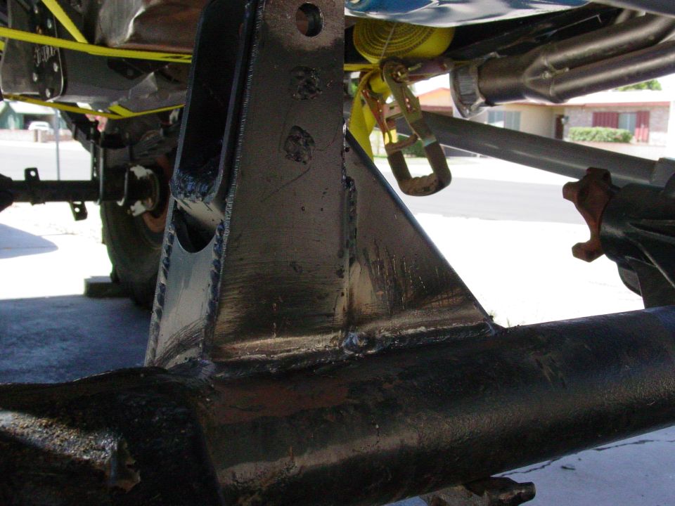 Freshly welded steel link bracket gusseted onto an axle housing, bare metal