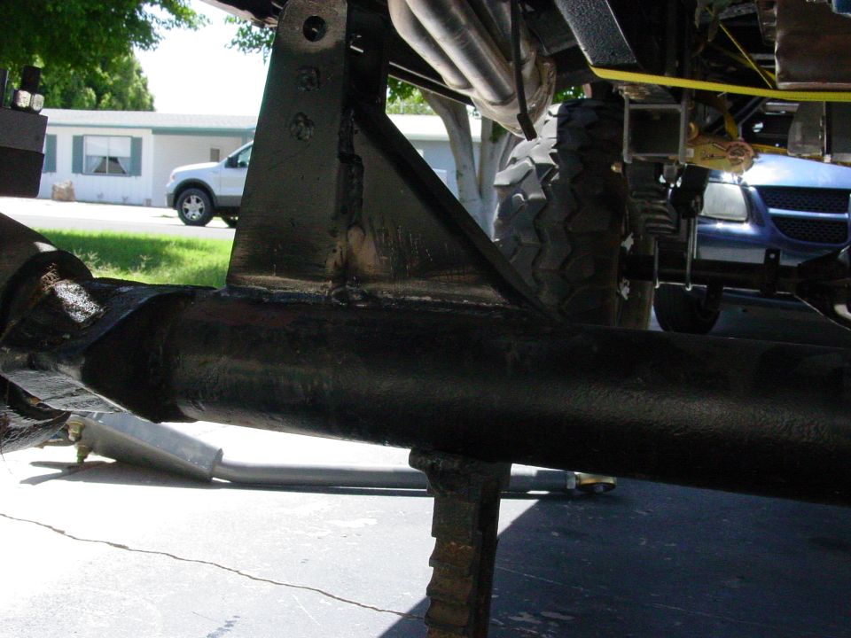 Underside of a vehicle's suspension with axle, bracket, and tire visible.