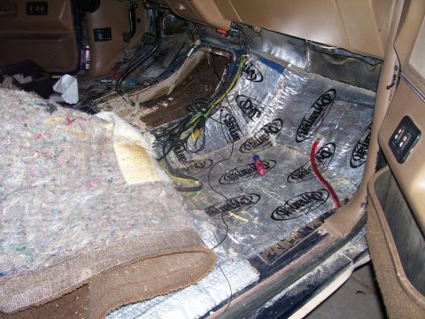 1991 Ford Bronco - The interior of a vehicle is shown with the carpet and sound deadening material removed from the floor. Wires and insulation are visible, a…