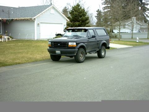 1995 Ford Bronco - This Ford Bronco is parked on the side of the road in front of a residential house.