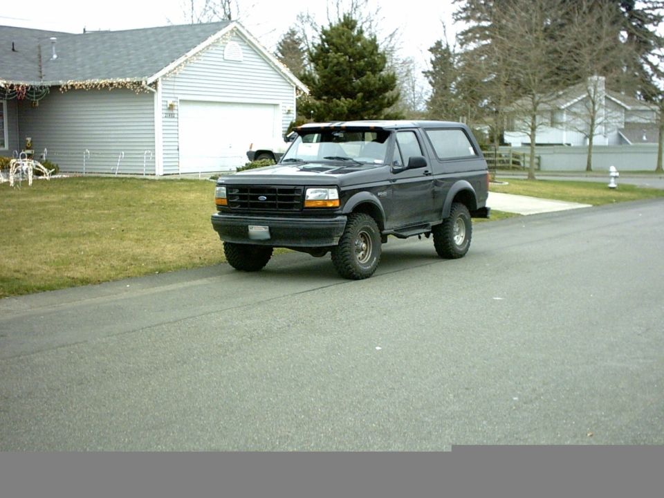 Black lifted Ford Bronco SUV parked on a street, 3/4 front view