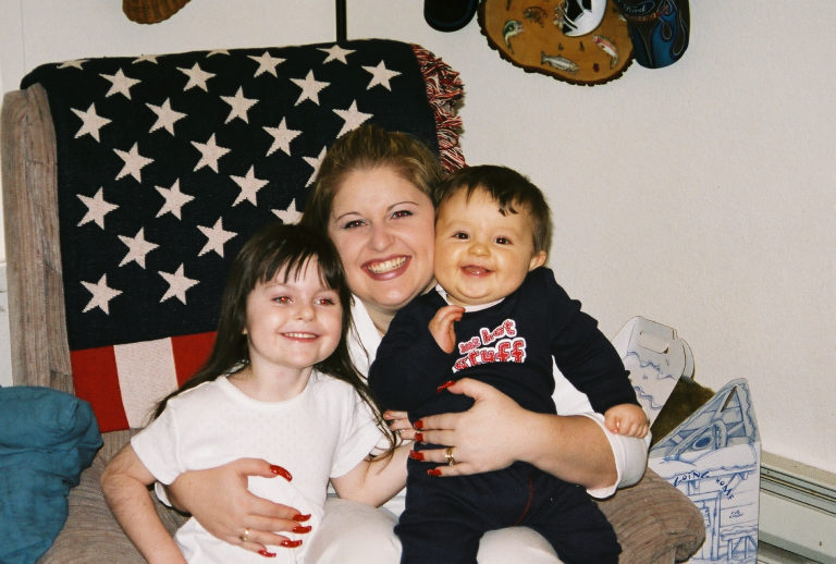 Woman with a baby and a young girl in front of an American flag blanket