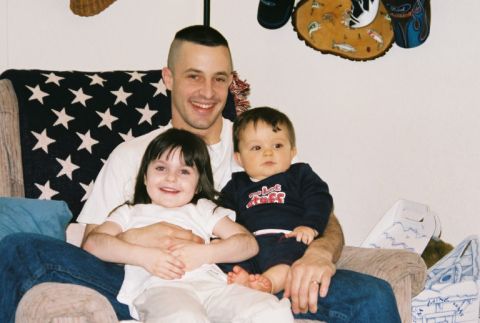 1995 Ford Bronco - A father sits with his two young children, a girl and a baby, on a couch.