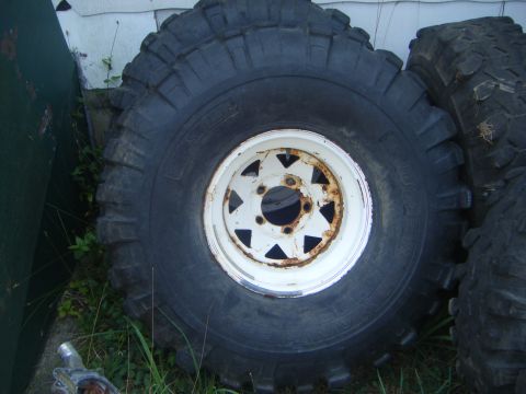 1979 Ford F-250 - A close-up of a large off-road tire mounted on a white wheel, showing its tread pattern.