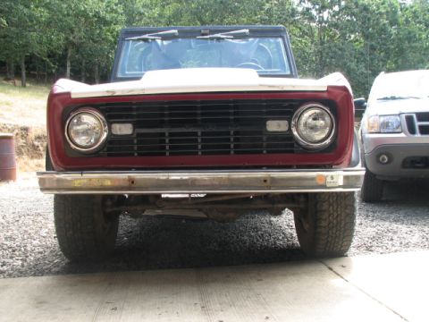 1968 Ford Bronco - Front view of a 1968 Ford Bronco with a red grille and white hood, parked outdoors.