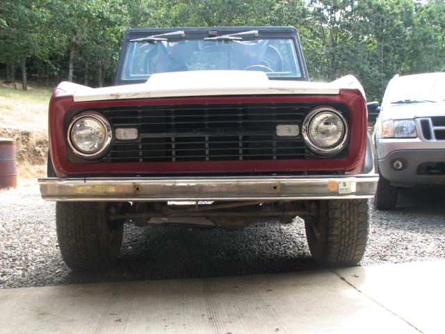 1968 Ford Bronco front grille, red and white body, chrome bumper, parked next to a silver SUV
