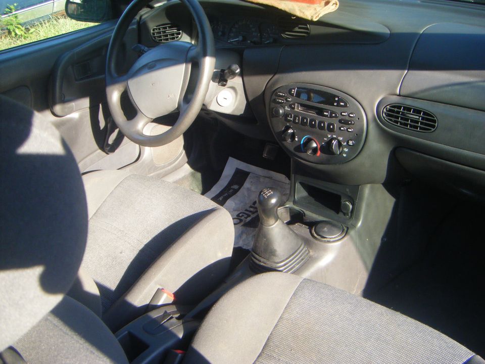 Interior of a car with gray seats, dashboard, steering wheel, and radio. Manual transmission shifter is visible