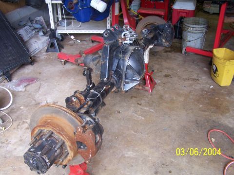 1979 Ford F-150 - A vehicle's front axle assembly, complete with disc brakes, is shown disassembled and supported by jack stands.