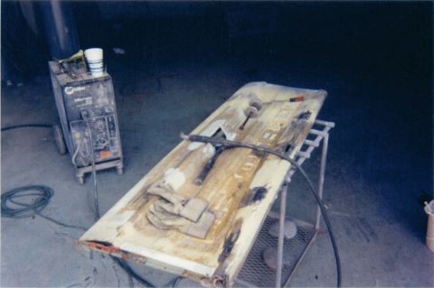 1976 Ford F-100 - A truck door is on a stand, being worked on next to a welding machine.