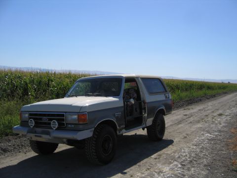 1991 Ford Bronco - Two-tone 1991 Ford Bronco with the driver's door open sits on a dirt road.
