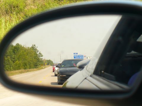 1993 Ford Probe - Traffic on the highway viewed through a side mirror, with multiple cars ahead.