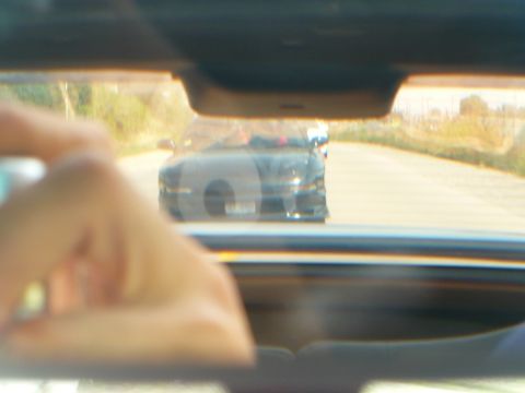 1993 Ford Probe - A dark sedan is visible through the windshield of another car on a road.