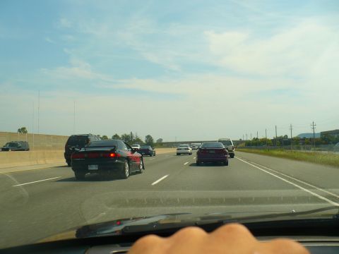 1993 Ford Probe - A red 1993 Ford Probe is seen from behind on a sunny day on the highway.